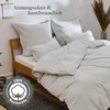 A bed with light gray bedding, pillows, and a duvet. Anteprima dell’immagine prodotto