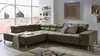 A modern living room with a large sectional sofa, a floor lamp, and shelves with decorative items.