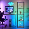 A modern gaming or office setup with a computer, chair, and a display shelf, all illuminated by colorful LED lights. Produktbild-Vorschau