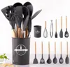 A collection of silicone kitchen utensils with wooden handles, neatly arranged in a dark gray holder, with additional utensils displayed in a row next to it. Náhľad obrázku produktu