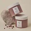 Two jars of Beauty of Joseon Red Bean Refreshing Pore Mask are displayed next to a rock and some red beans. Produktbild-Vorschau