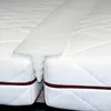 A close-up view of a white mattress topper bridge placed between two mattresses. Produktbild-Vorschau
