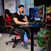 A man is sitting in a gaming chair at a desk with a computer, talking on the phone. Náhled obrázku produktu