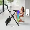 A woman is adjusting the seat of a black exercise bike in a bright, modern room. Dimensions and user weight/height recommendations are overlaid on the image. Anteprima dell’immagine prodotto