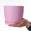 Hands holding a pink flower pot with a saucer. Anteprima dell’immagine prodotto