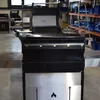 A close-up view of a black and silver grill in a warehouse or workshop setting. Anteprima dell’immagine prodotto