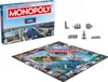 A Monopoly board game box and board, along with game pieces, are displayed on a white background. Produktbild-Vorschau