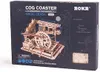 The image shows the packaging of a wooden model kit, specifically a cog coaster. Podgląd zdjęcia produktu