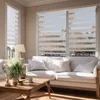 A living room scene with a white sofa and a wooden coffee table in front of windows with striped blinds. Podgląd zdjęcia produktu