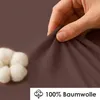 A hand is shown stretching a brown fabric, with cotton balls in the foreground. Produktbild-Vorschau