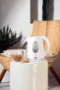 A white electric kettle sits on a white stool next to a bowl of cookies, with a plant and chair in the background. Voir les images du produit