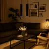 A dimly lit living room scene with a sectional sofa, coffee table, and a rocking chair. Náhled obrázku produktu