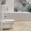 A modern bathroom with a wall-mounted toilet and a bathtub. Podgląd zdjęcia produktu
