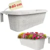 A collage showing two views of a white rattan-look balcony planter. The top image shows the planter empty with a tag indicating '60 cm'. The bottom image shows the planter filled with colorful flowers. Produktbild-Vorschau