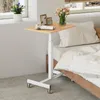 A mobile, height-adjustable side table with a wooden top is placed next to a bed, with a vase of flowers and framed pictures on top. Produktbild-Vorschau
