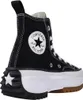 A black Converse high-top sneaker with a white platform sole and a brown sole. Voir les images du produit