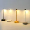 Four modern LED table lamps in different colors are lined up against a white wall. Produktbild-Vorschau