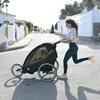 A woman is running with a black stroller on a street. Produktbild-Vorschau