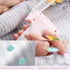 A collage showing a pink tagging gun being used to attach a plastic fastener to bedding, with close-ups of the fasteners and the gun mechanism. Produktbild-Vorschau