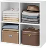 A white cube shelf unit filled with folded clothes, a hat, a box, and a cosmetic case. Náhľad obrázku produktu
