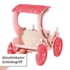 A pink toy carriage with decorative brown swirls and a canopy, shown against a white background. A hand is visible near the bottom, interacting with the carriage. Produktbild-Vorschau