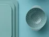 A light blue colander is shown against a light blue background, with layered rounded rectangles on the left side. Produktbild-Vorschau