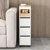 A slim white cabinet with wooden accents and drawers is placed next to a sofa, against a wood-paneled wall. Produktbild-Vorschau