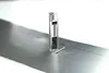 A silver marking tool with a clear casing and a silver cap is placed on a metal surface. A thin metal rod is next to it, and a line of small marks is visible on the metal surface. Náhľad obrázku produktu