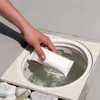 A hand is placing a white packet into a pool skimmer. Anteprima dell’immagine prodotto