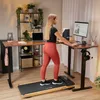 A woman is using a treadmill desk in a home office setting. Produktbild-Vorschau