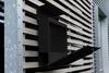 A black mailbox mounted on a wooden slatted wall. Anteprima dell’immagine prodotto