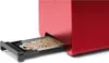 A close-up of a red toaster with its crumb tray extended and filled with crumbs. Voir les images du produit