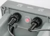 Close-up view of the back of a gray electronic device, showing two black cable connectors and a red button. Produktbild-Vorschau