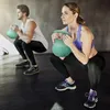 A man and a woman are performing kettlebell squats in a gym. Náhled obrázku produktu