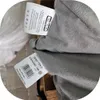 Close-up of two tags attached to a gray fabric product. Náhled obrázku produktu