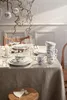 A beautifully set dining table with festive decorations, including hanging ornaments and branches, suggesting a holiday meal. Podgląd zdjęcia produktu