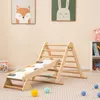A wooden climbing triangle with a slide, set up indoors on a carpeted floor. There are two framed pictures of animals on the wall behind it, and a bookshelf to the right. Produktbild-Vorschau