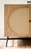 A close-up view of a wooden sideboard with a rattan woven door and black metal legs. Produktbild-Vorschau