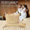 A wooden sauna bucket and ladle are in the foreground, with a couple in bathrobes in the background. Produktbild-Vorschau