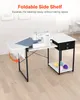 A sewing machine is placed on a white folding table with a black metal frame. The table has a foldable side shelf and a drawer unit with two drawers. There are also colorful balls of yarn on a lower shelf. Podgląd zdjęcia produktu