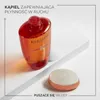A bottle of Kérastase shampoo and a small round product are displayed on a white surface with a white ribbon. Produktbild-Vorschau