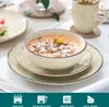 A set of beige ceramic dishes with a bowl of soup and a mug of tea on a table. Náhled obrázku produktu