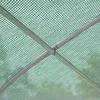 Close-up view of the internal structure of a greenhouse, showing the metal frame covered by a green mesh-like plastic sheeting. Produktbild-Vorschau