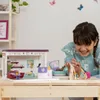 A young girl is playing with a toy pet salon playset. Produktbild-Vorschau