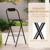 A black folding bar stool is shown outdoors on a patio, with text overlays highlighting its features. Produktbild-Vorschau