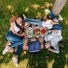 A family is having a picnic on a blanket in the grass. Náhled obrázku produktu