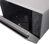 Close-up view of the inside of a microwave oven with the door open, showing the turntable and a control panel with text. Produktbild-Vorschau
