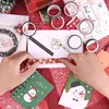 Hands are shown decorating a Christmas card with washi tape, surrounded by various rolls of washi tape and Christmas-themed stationery. Produktbild-Vorschau