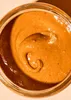 A close-up overhead view of peanut butter in a jar. Produktbild-Vorschau