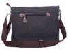 The back view of a dark gray canvas messenger bag with brown faux leather accents and a brown strap, shown against a white background. Podgląd zdjęcia produktu